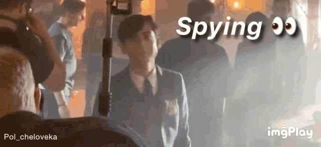 a man in a suit and tie is standing in front of a camera with the words spying written above him