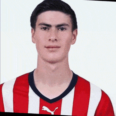 a young man is wearing a red and white striped soccer jersey .