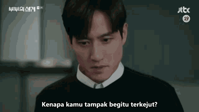 a man in a black sweater and white shirt says kenapa kamu tampak begitu terkejut