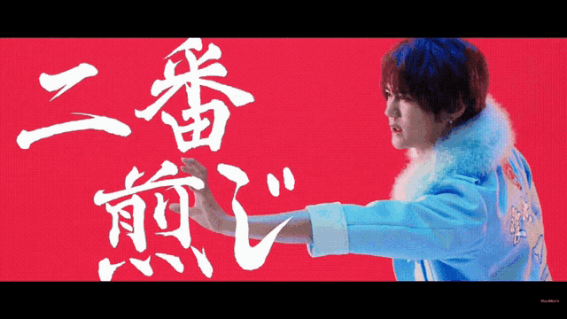 a man in a blue jacket stands in front of a red background with chinese characters