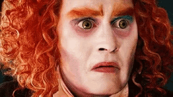 a close up of a person 's face with red curly hair and makeup .
