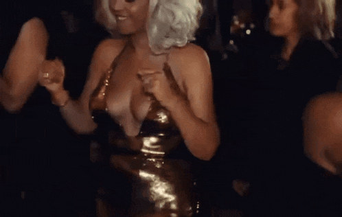 a woman in a very low cut dress is dancing in a crowd of people .