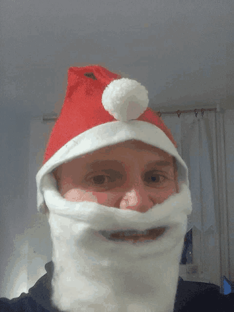 a man wearing a santa hat and beard is smiling