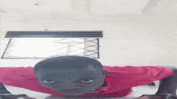 a young man in a pink shirt is doing push ups on a table .