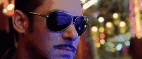 a man wearing sunglasses and a mustache looks at the camera .