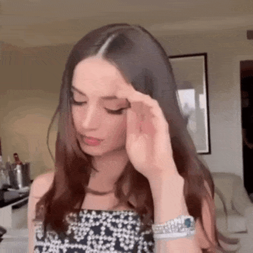 a woman in a black and white dress is holding her head .