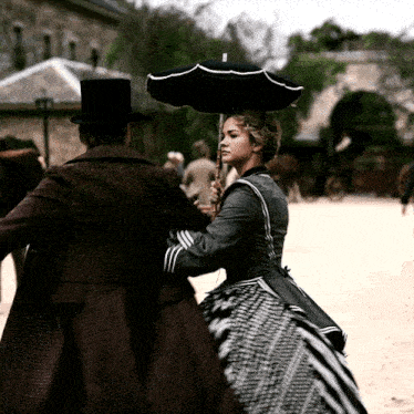 a man in a top hat holds an umbrella over a woman in a plaid dress