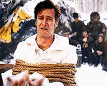 a man in a white shirt is tied up with a rope