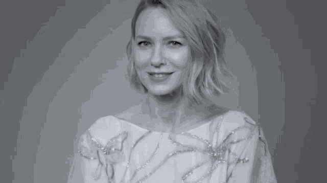 a black and white photo of a woman in a white dress smiling and giving the middle finger .