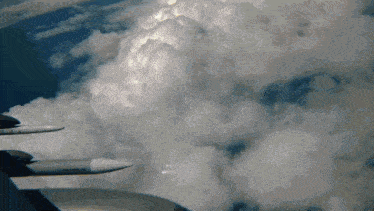 a plane is flying through a cloudy sky with a jet engine visible