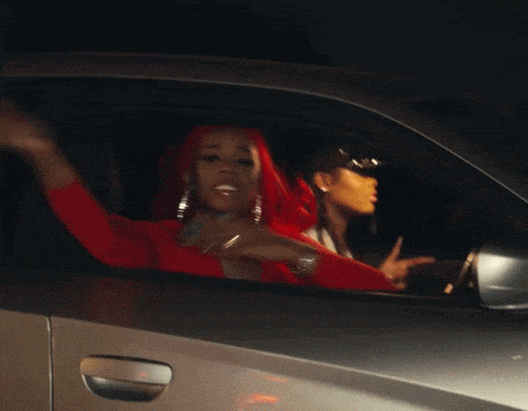 a woman in a red dress is driving a car