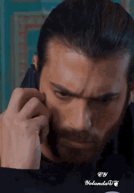 a man with a beard is talking on a cell phone with the name yolanda on the bottom right