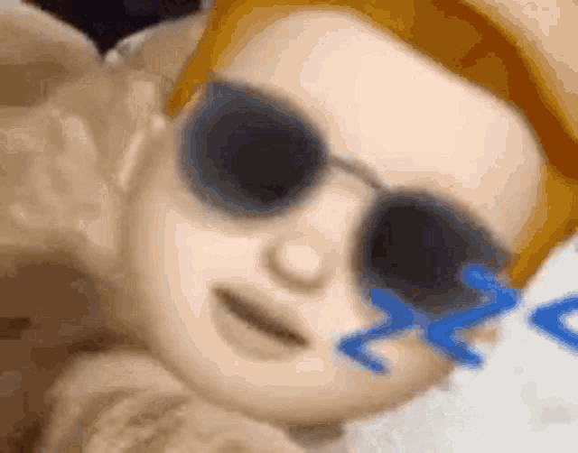 a close up of a person wearing sunglasses with a blue sticker on their eye .