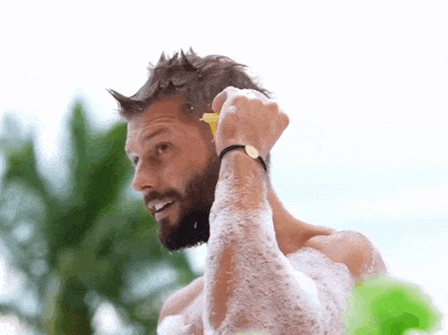 a man with a beard is washing his hair with soap