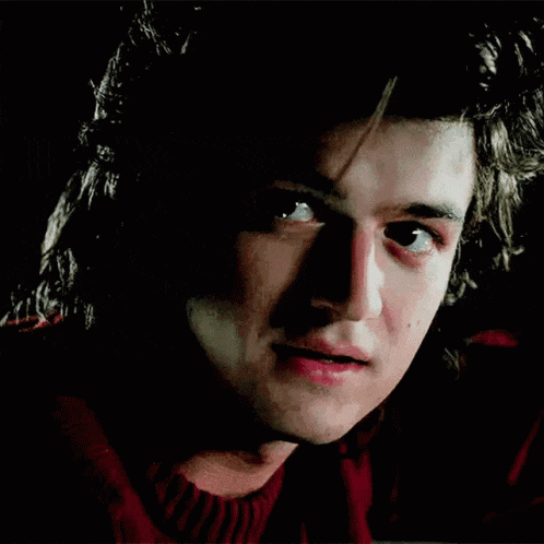 a close up of a man 's face with his eyes closed and a red sweater .