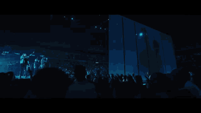 a group of people standing on a stage with a blue light behind them