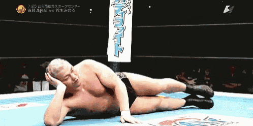 a man is laying on the ground in a wrestling ring with a banner behind him that says ' a '