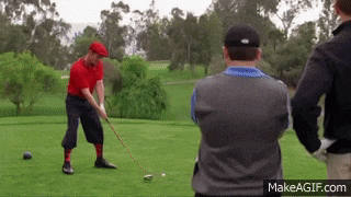 a man in a red shirt is swinging a golf club on a green