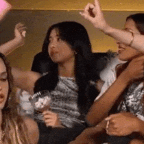 a group of women are sitting on a couch with their hands in the air