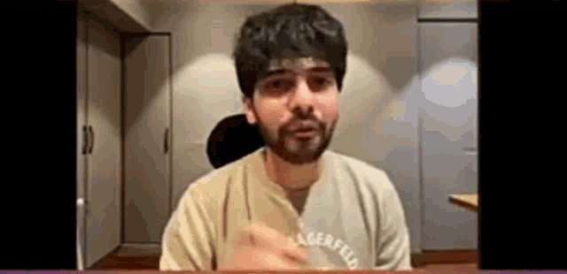 a man with a beard is sitting at a table and talking to someone .