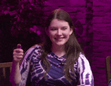 a woman in a tie dye shirt is smiling and holding a lighter