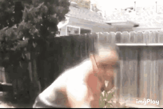 a man is standing in front of a fence in a yard .