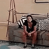 a woman is sitting on a couch in a living room with a lamp .