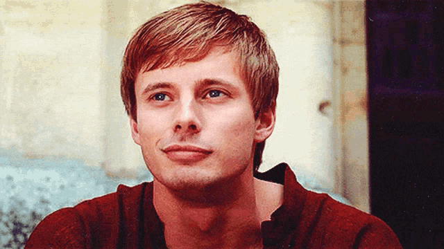 a close up of a young man 's face with a red shirt on