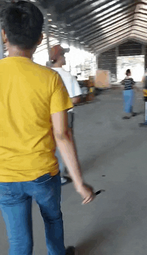 a man in a yellow shirt and blue jeans is standing in a warehouse