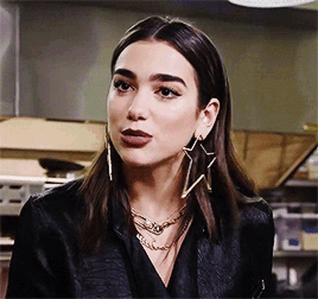 a close up of a woman wearing a black shirt and earrings