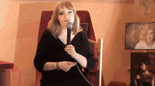 a woman singing into a microphone in front of a chair