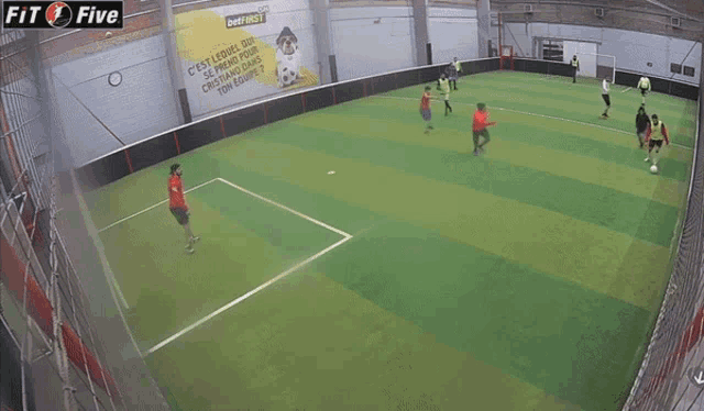 a group of soccer players are playing on a field with a sign that says fit five in the background