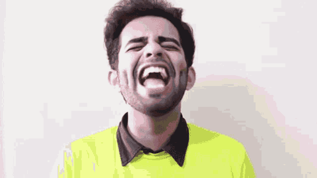 a man with a beard and a yellow shirt is screaming with his mouth wide open .