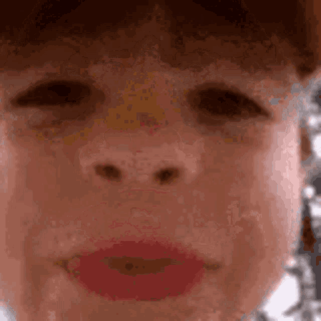 a close up of a child 's face with red lipstick on his lips .
