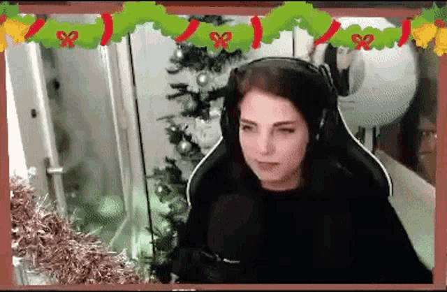 a woman is sitting in front of a christmas tree wearing headphones .