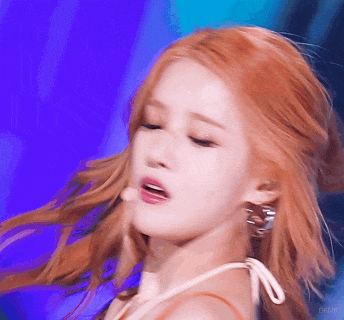 a close up of a woman 's face with red hair against a blue background .
