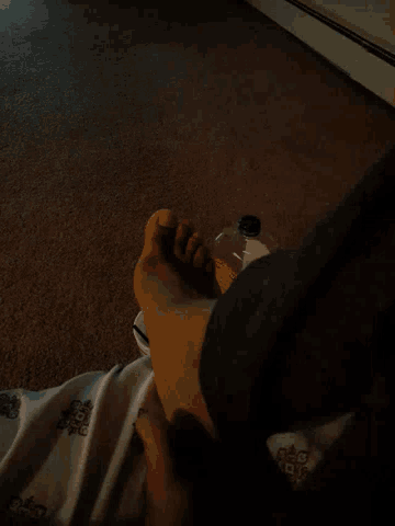 a person 's foot rests on a carpet next to a bottle that says ' vinegar ' on it