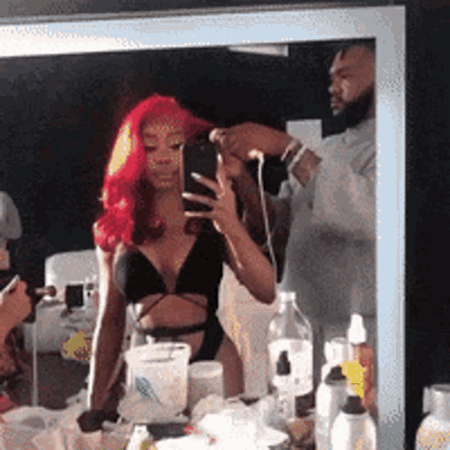 a woman with red hair is taking a picture of herself in the mirror