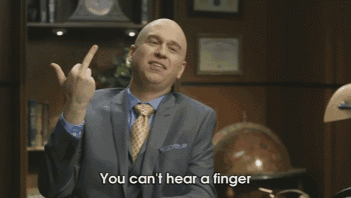 a bald man in a suit and tie is giving the middle finger and says you can t hear a finger