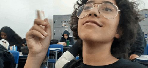 a boy wearing glasses holds up a piece of paper