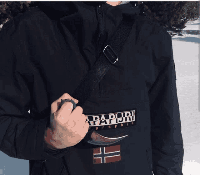 a man wearing a black napapijri jacket holds a knife