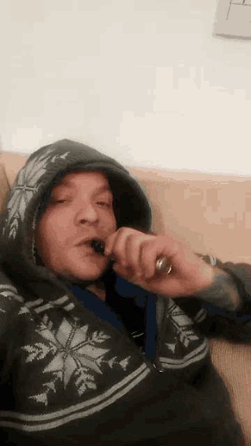 a man wearing a hoodie is smoking a cigarette