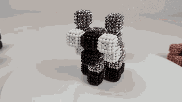 a person is holding a bunch of metal balls on a white surface