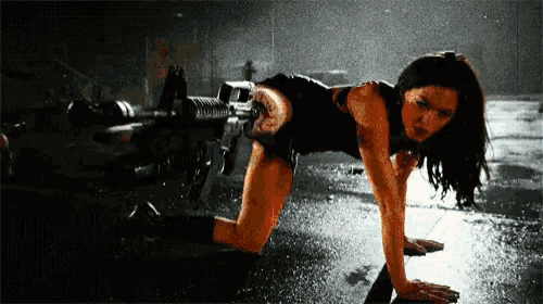 a woman is crawling on the ground with a gun in her hand .
