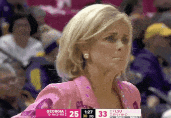 a woman in a pink jacket stands in front of a scoreboard that says georgia