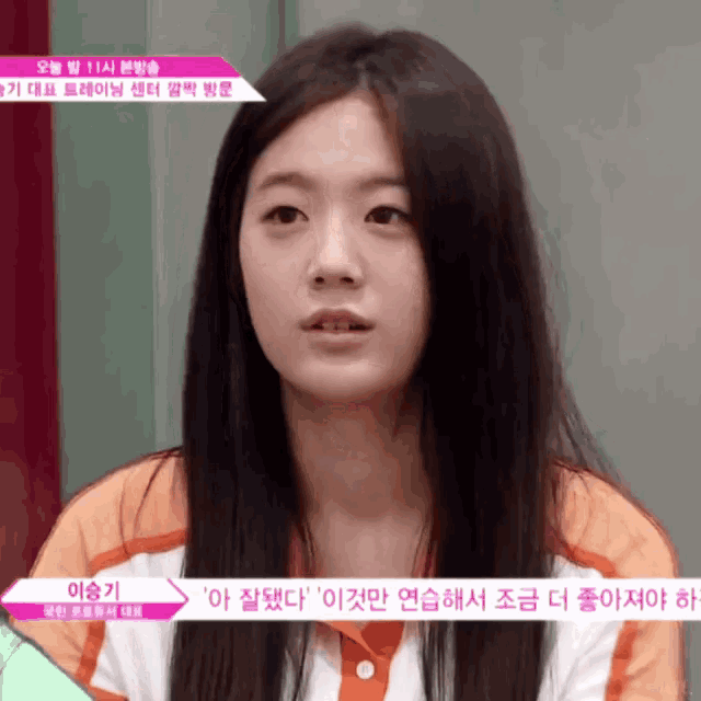 a girl with long black hair is looking at the camera with a sign that says ' 이승기 ' on it