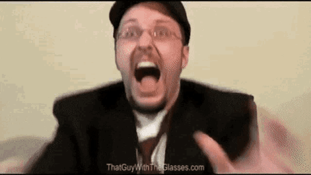 a man with glasses and a hat is making a funny face .