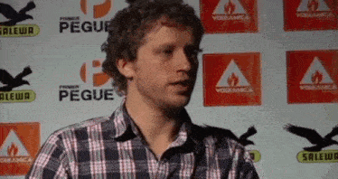 a man in a plaid shirt stands in front of a wall that says primer pegue on it