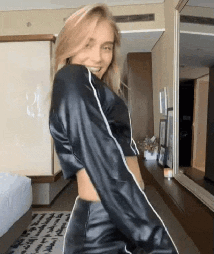 a woman in a black crop top and pants is dancing in a room