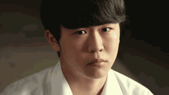 a close up of a young boy 's face with a white shirt on